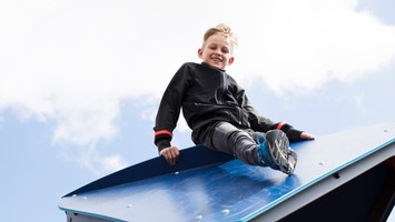 en elev sitter på taket på en klätterställning