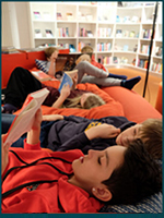 Läsande elever i en mjuk liggmöbel.