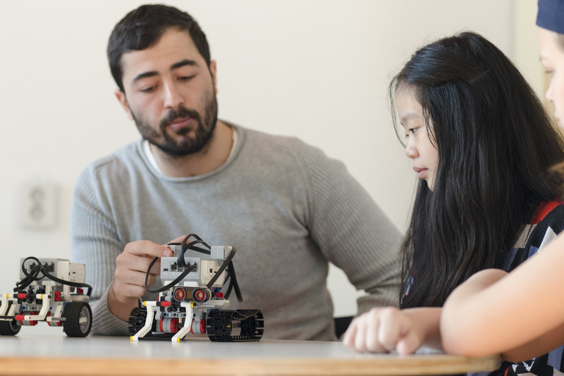 en lärare och två elever bygger en legorobot