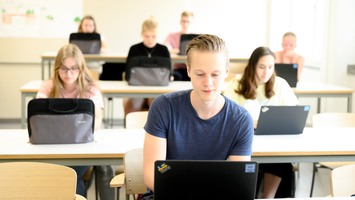 elever sitter vid borden med datorerna framför sig