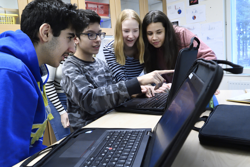 En grupp elever som tittar på något på en dator i ett klassrum