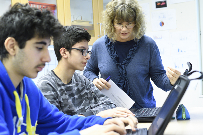 Elever och lärare arbetar med laptops