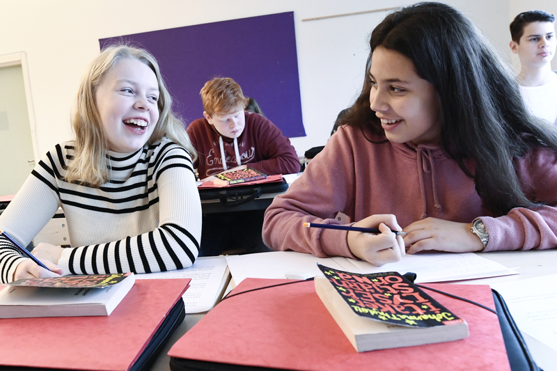 Två kvinnliga elever skrattar tillsammans i klassrummet