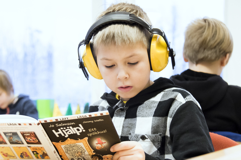 en pojke läser med hörlurar på för att inte störas av ljud