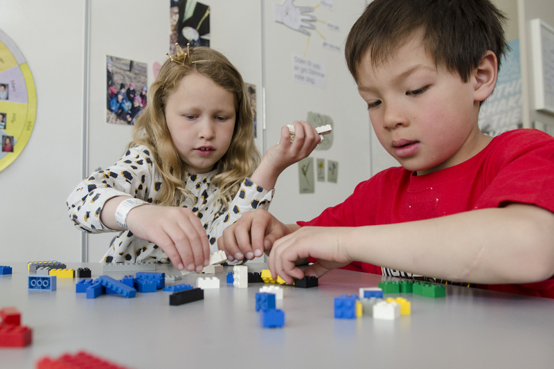 flicka och pojke bygger med lego på ett bord