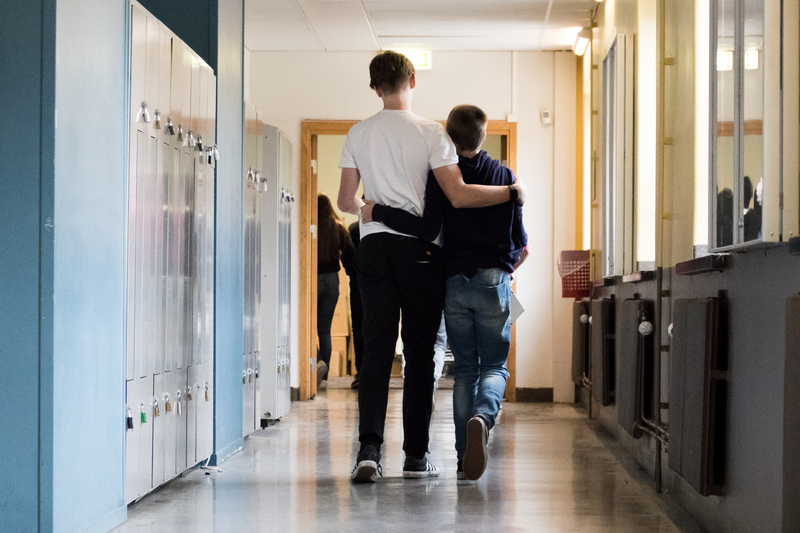 Två elever håller om varandra när de går i en skolkorridor