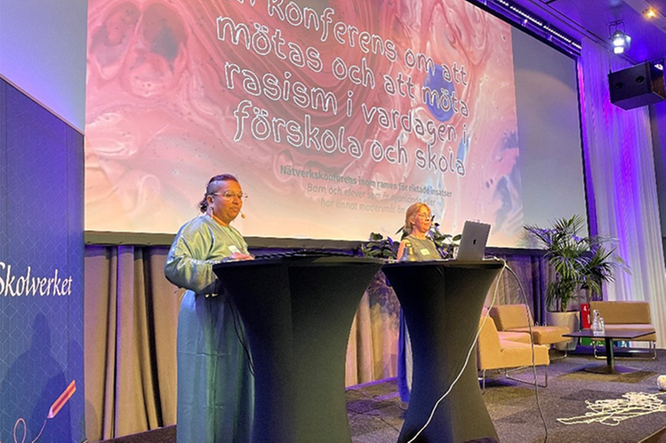 Bild på två personer som pratar på en scen på en konferens.