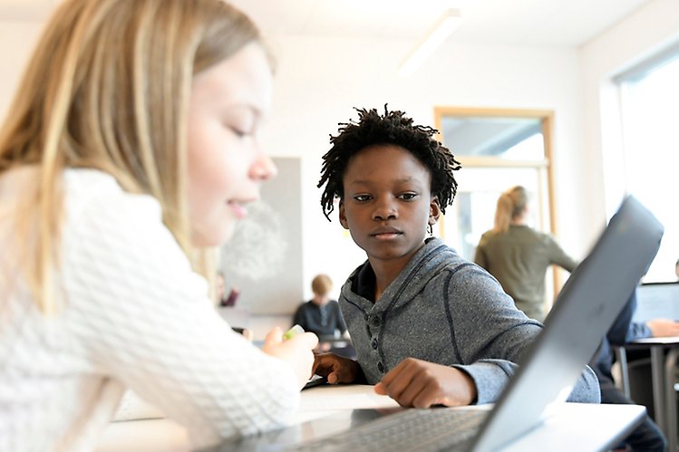 Elever i ett klassrum arbetar vid en dator