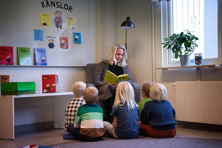 En vuxen läser för en grupp barn.
