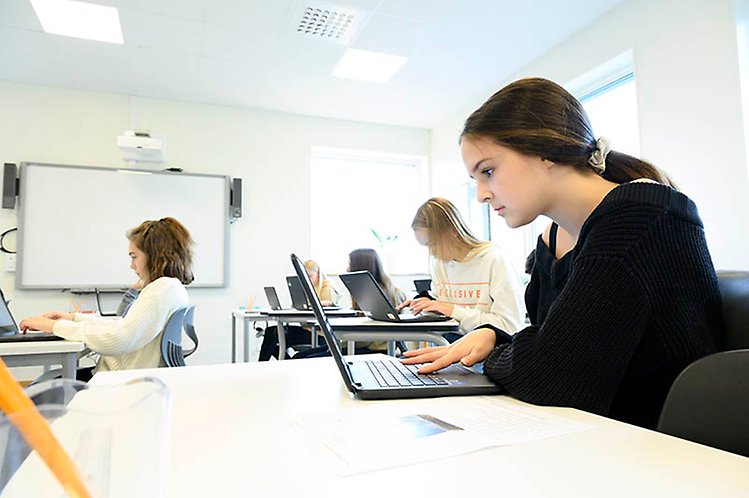 Bild av ett klassrum där elever skriver deltar i en undersökning digitalt